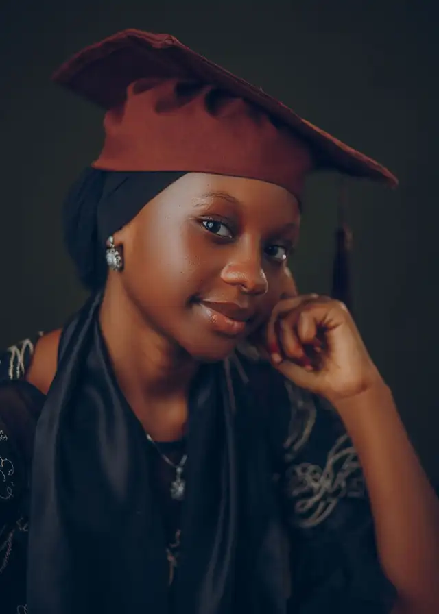 Young graduate smiling in a maroon cap and gown. Stock photograph by Ab Pixels on Pexels, not a Nafasi student.